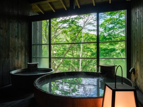 a bath tub in a room with a large window at Nagominoyado Hanagokoro - Reopening in Mar 2024 in Hakone