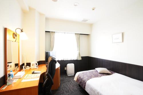 Habitación de hotel con cama y escritorio en ホテル大藏, en Kanoya