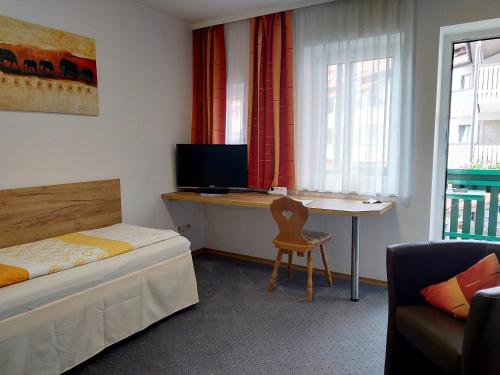 
a room with a bed, desk, television and chair at Hotel Fortuna in Bad Gögging
