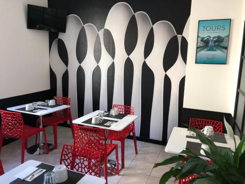 a restaurant with red chairs and tables and a wall at Hôtel Saint Eloi in Tours