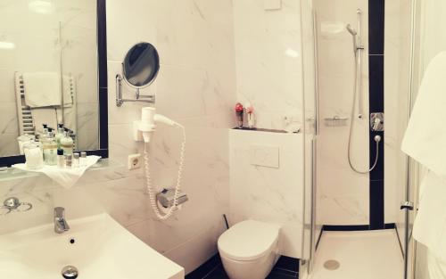 a white bathroom with a toilet and a shower at Panorama Hotel Gasthof Leidingerhof in Mondsee