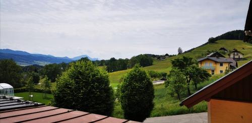 a view of a green hill with a house and trees at Panorama Hotel Gasthof Leidingerhof in Mondsee