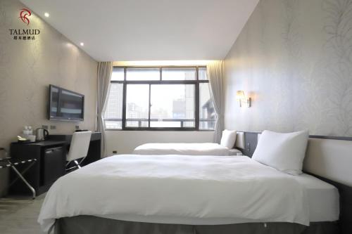 a hotel room with two beds and a television at Talmud Hotel Taichung in Taichung