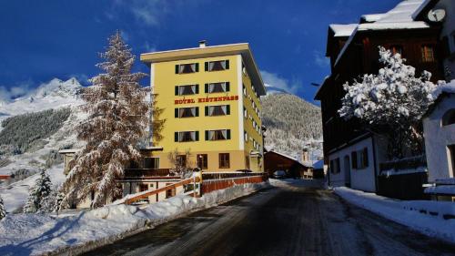 un edificio amarillo al lado de una calle cubierta de nieve en Hotel Kistenpass, en Brigels