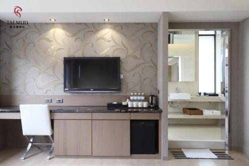 a bathroom with a flat screen tv on a wall at Talmud Hotel Taichung in Taichung