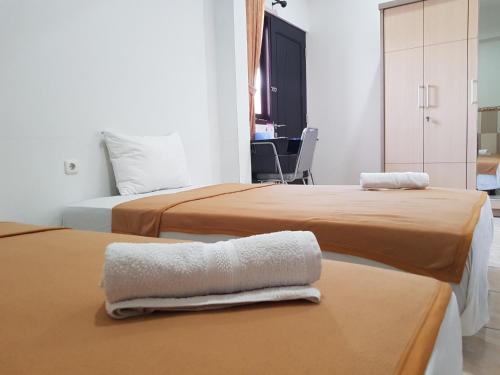 two beds in a hotel room with towels on a table at Villetta House Syariah in Kudus