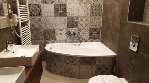 a bathroom with a tub and a sink at Vácz Hotel in Vác