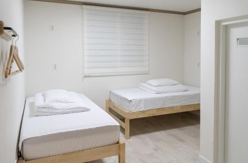 two beds in a room with a window at Hwarang Guesthouse in Gyeongju