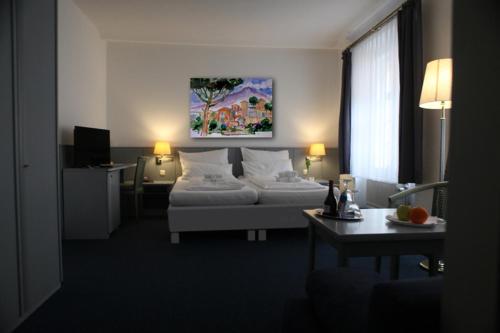 a hotel room with a bed and a table with a table at Altstadthotel Augsburg in Augsburg