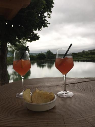 two glasses of wine and chips on a table near a lake at La Fontanella in Montecchia di Crosara