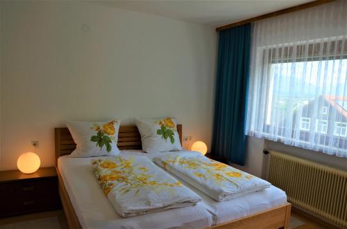 a bedroom with a bed with two pillows and a window at Ferienwohnung Walgaublick in Frastanz