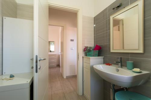 La salle de bains est pourvue d'un lavabo et d'un miroir. dans l'établissement Appartamento Calipso - MyHo Casa, à Tortoreto Lido
