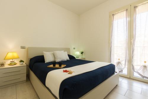 - une chambre avec un lit bleu et blanc et une fenêtre dans l'établissement Appartamento Calipso - MyHo Casa, à Tortoreto Lido