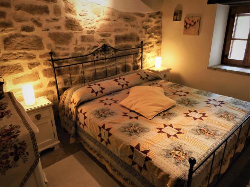 a bedroom with a bed with a stone wall at Casale Grillo in Cortona