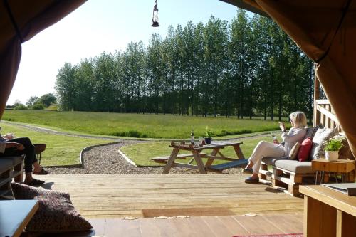 a group of people sitting on a wooden patio at Tall Trees Glamping in Baltonsborough