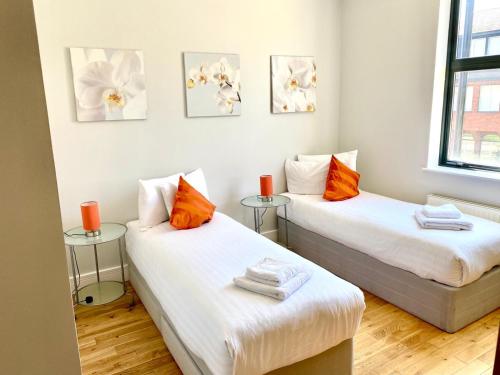 a room with two beds with orange and white pillows at Westciti Croydon Serviced Apartments in Croydon