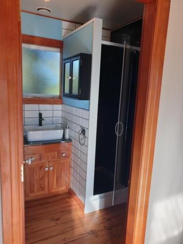 a bathroom with a sink and a shower at The Blackhouse Cottage in Hokitika