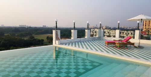 a swimming pool with two chairs and an umbrella on a building at The Glenburn Penthouse in Kolkata