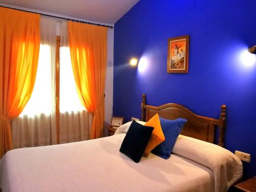 a bedroom with a bed with blue walls and a window at Hostal Restaurante Ego's in Campo de Criptana