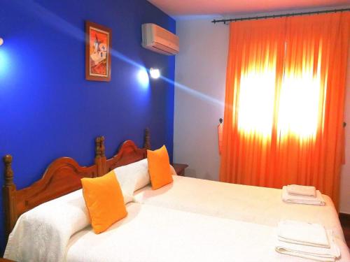 a bedroom with a bed with an orange curtain at Hostal Restaurante Ego's in Campo de Criptana