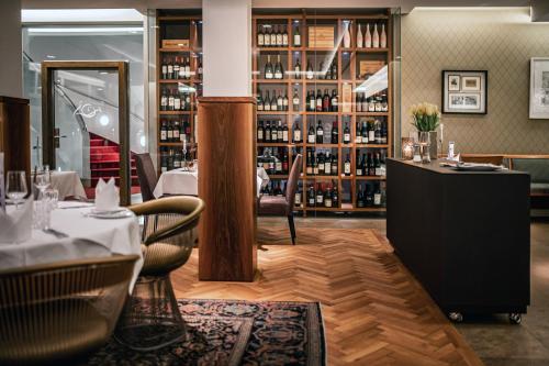 バート・ザウルガウにあるRomantik Hotel Kleber Postのテーブルと椅子、ボトルワインの棚が備わるレストラン