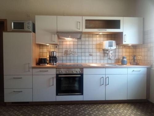 a kitchen with white cabinets and a stove top oven at Ferienhaus an der Mosel in Senhals