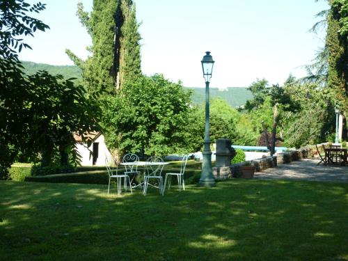 a table and chairs in a park with a street light at Chambres d'hôtes Maison Redon in Tour-de-Faure