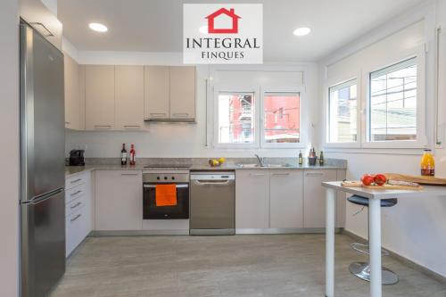 a kitchen with white cabinets and a stainless steel refrigerator at Sea La Vie Home Palamós in Palamós