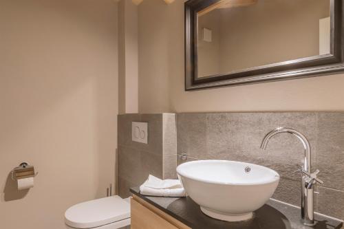 een badkamer met een wastafel, een toilet en een spiegel bij Ahorn in Interlaken