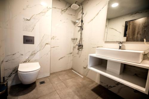 a white bathroom with a toilet and a sink at Calda Resort in Kalivia Poligirou