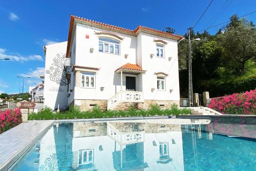 a villa with a swimming pool in front of a house at Casa do Vidoeiro in Seia