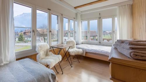 a bedroom with a bed and two chairs and windows at Hasel in Interlaken