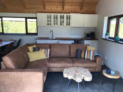 a living room with a brown couch and a kitchen at Heerlijk huisje vlakbij de duinen van Oostvoorne in Oostvoorne