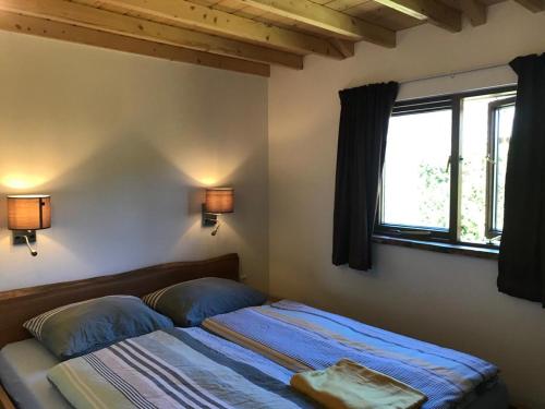 a bedroom with a bed with two pillows and a window at Heerlijk huisje vlakbij de duinen van Oostvoorne in Oostvoorne