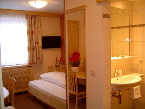a bedroom with a bed and a sink and a mirror at Pension Waldhof in Lech am Arlberg