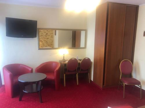 a room with chairs and a table and a tv at Hotel Sekwana in Częstochowa