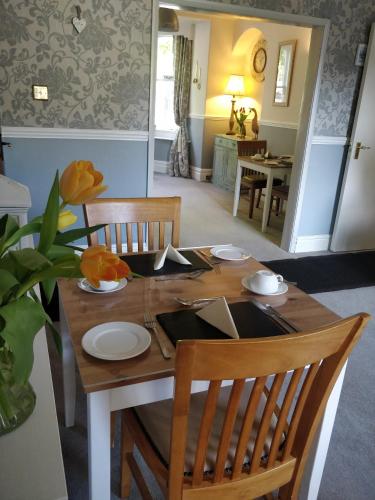 a dining room table with two chairs and a table with plates andoverty at Melbourne Guest House in Bowness-on-Windermere