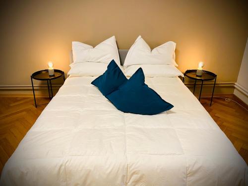 a large white bed with two blue pillows on it at Crops City Stay in Trieste