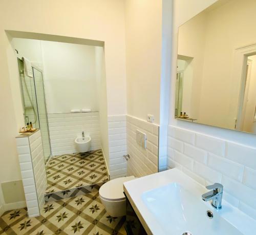 a white bathroom with a toilet and a sink at Crops City Stay in Trieste