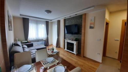 een woonkamer met een bank en een tafel met stoelen bij Holiday Spa Lux Apartment in Zlatibor