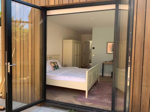 a room with a bed inside of a glass door at Charming private guesthouse Air by the Beach in Zandvoort