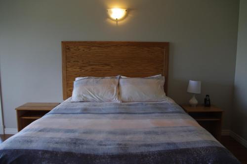 a bed with a wooden headboard in a bedroom at Motel des Mariniers in Kamouraska