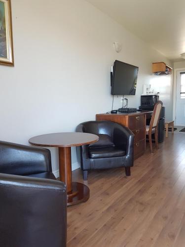 a living room with a table and chairs and a tv at Motel des Mariniers in Kamouraska