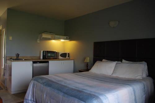 a bedroom with a large bed and a kitchen at Motel des Mariniers in Kamouraska