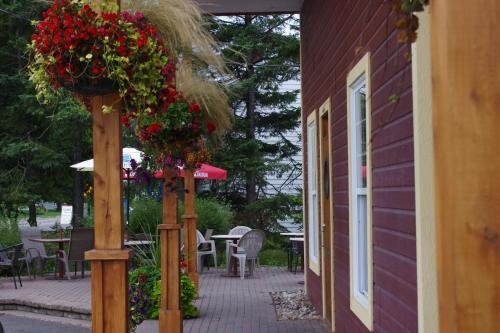 a patio with flowers on posts and a building at Motel des Mariniers in Kamouraska