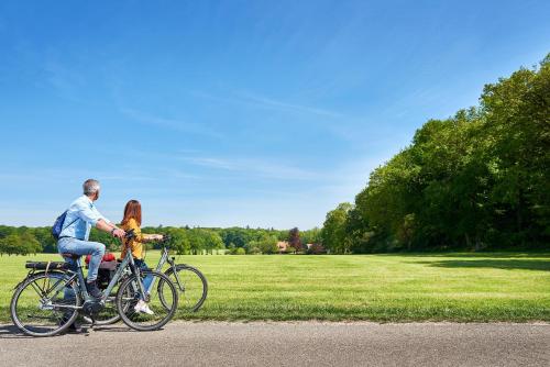 a man and a woman riding a bike in a park at Hotel 't Kruisselt in De Lutte