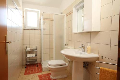 a white bathroom with a toilet and a sink at House Antonac in Novigrad Istria