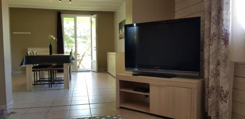 uma sala de estar com uma televisão de ecrã plano num suporte em COTTAGE privé avec TERRASSE et PISCINE - bord de LAC & FORÊT em Miramont-de-Guyenne