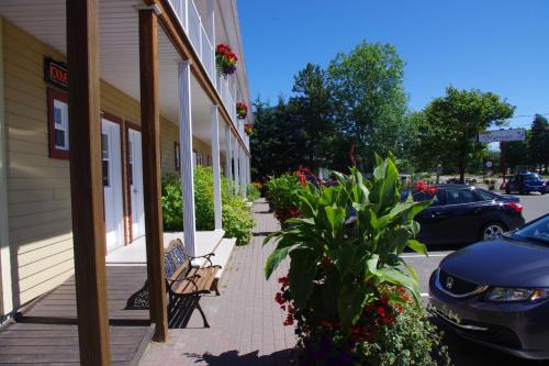 a porch of a building with a bench and flowers at Motel des Mariniers in Kamouraska