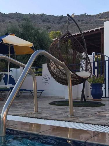 a hammock hanging from a swing next to a pool at Chrysanthi studios and apartments Pefkos in Pefki Rhodes